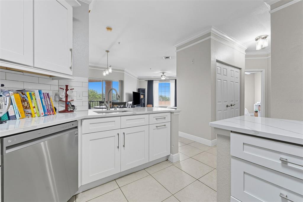 A kitchen with white cabinets, stainless steel appliances, and a view into the living area — 4333 BAYSIDE VILLAGE DRIVE UNIT 304, TAMPA, FL