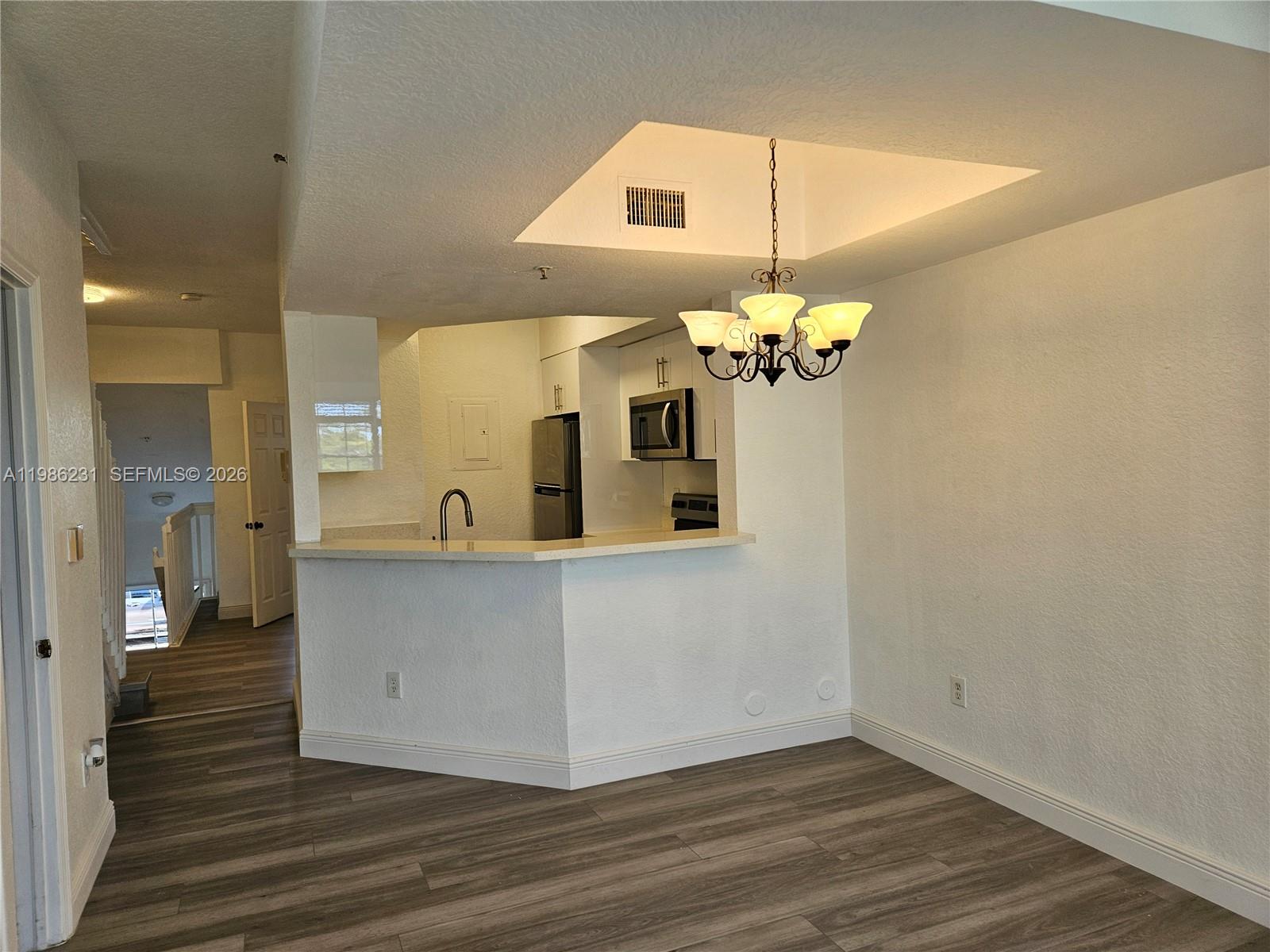 A kitchen with a breakfast bar and dining area featuring wood-look flooring and a chandelier — 751 SW 148th Ave # 1012, Sunrise FL 33325, SUNRISE, FL