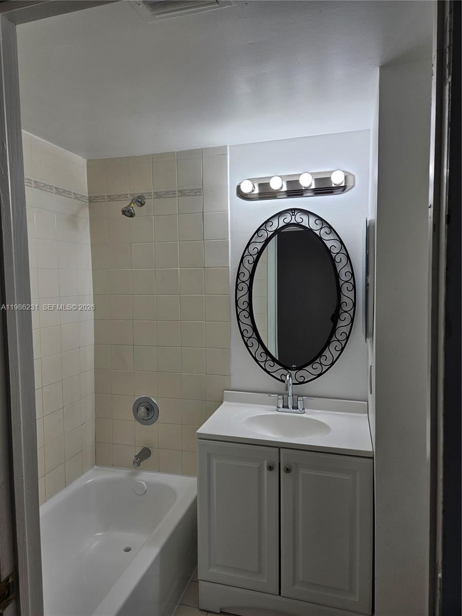 A bathroom features a white vanity, an oval mirror, and a tiled shower-tub combination — 751 SW 148th Ave # 1012, Sunrise FL 33325, SUNRISE, FL