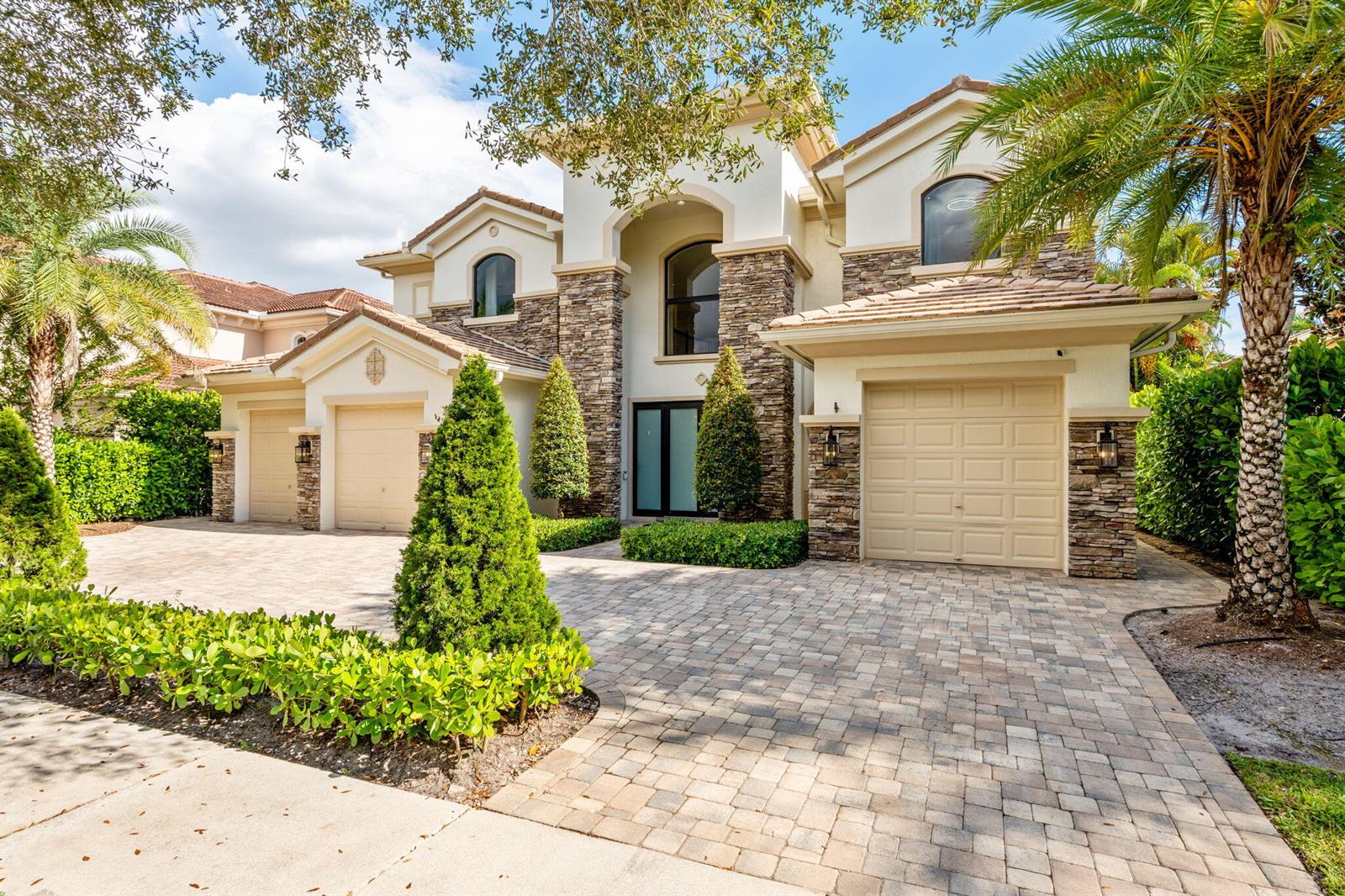 A two-story house with a stone facade, three garage bays, and a paved driveway — 647 Edgebrook Lane, Royal Palm Beach FL 33411, ROYAL PALM BEACH, FL