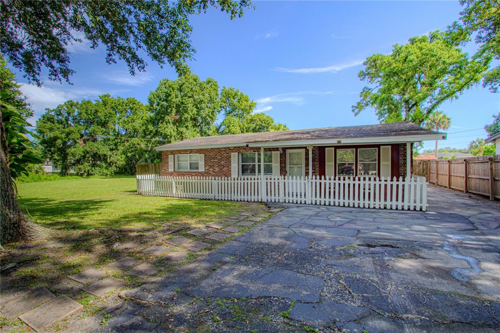 A single-story brick house with a white picket fence and a paved driveway — 1026 SARITA STREET, SANFORD, FL