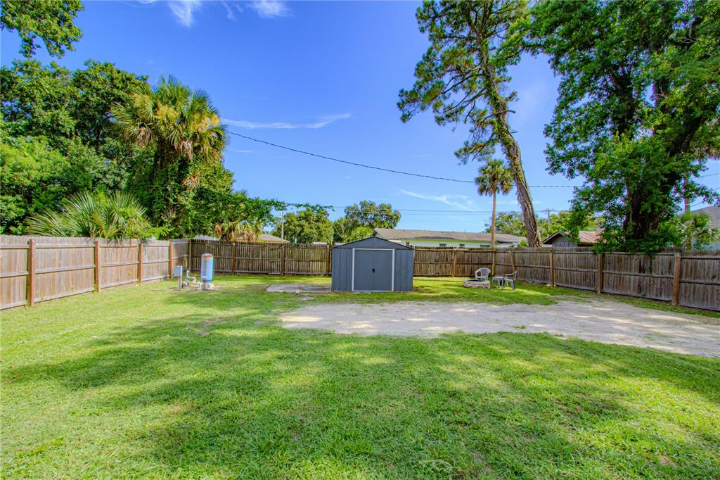 A fenced backyard features a grass lawn, a storage shed, and a well pump — 1026 SARITA STREET, SANFORD, FL