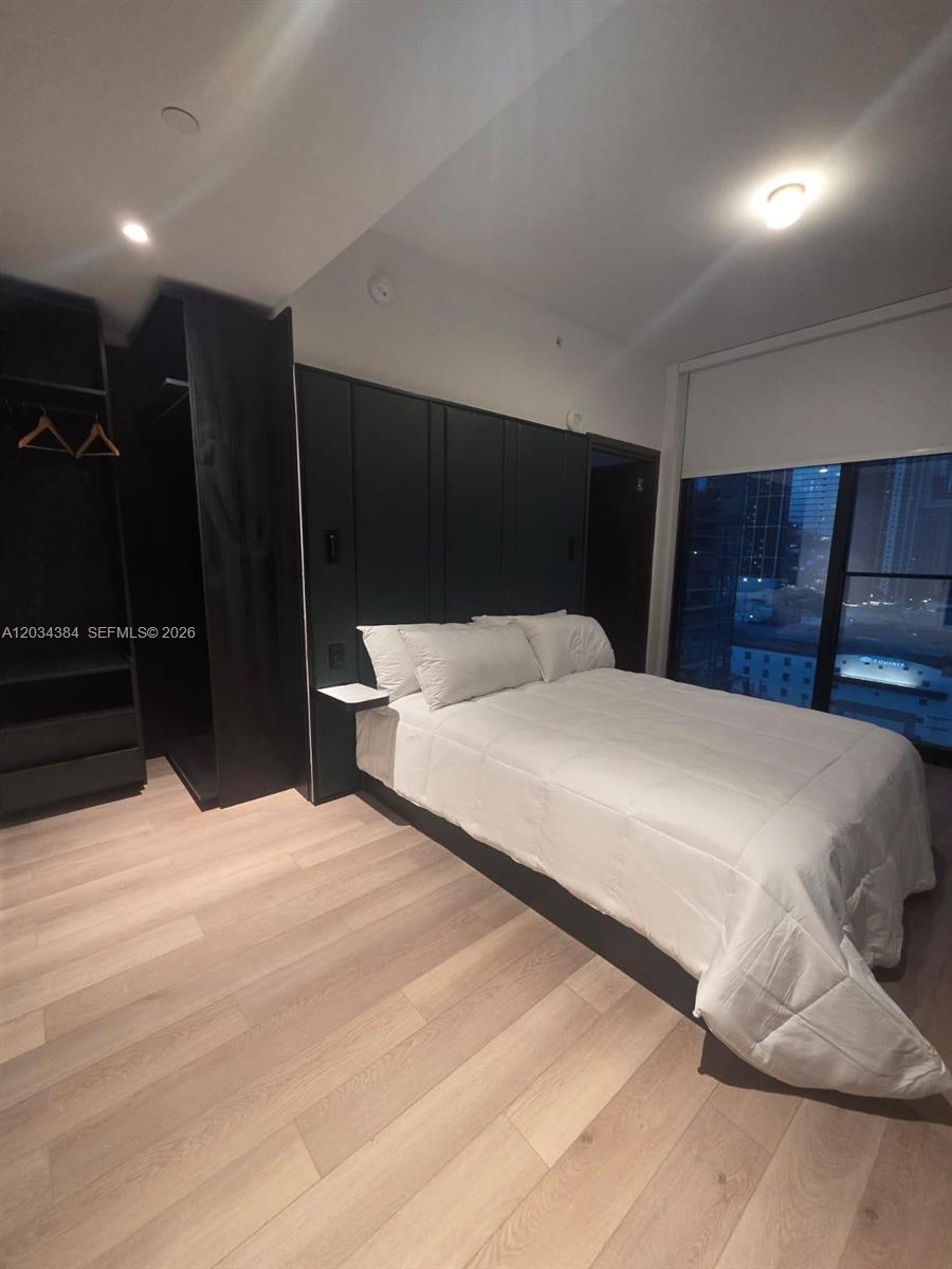 A bedroom features light wood flooring, a black paneled accent wall, and an open closet — 20 NE 11 # 2208, South Miami FL 33132, SOUTH MIAMI, FL