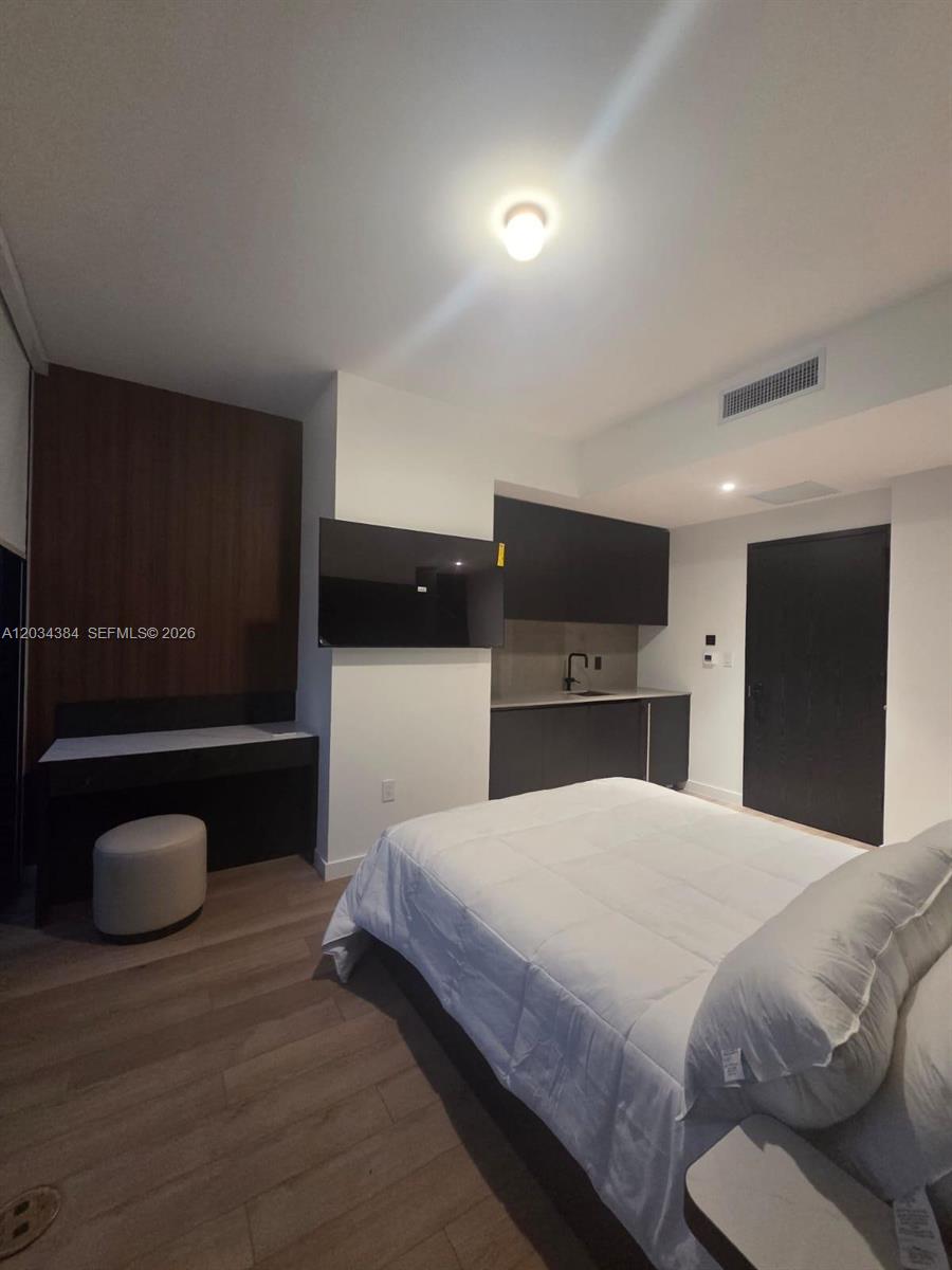 A bedroom features a bed, a small kitchenette, a desk, and dark wood accents — 20 NE 11 # 2208, South Miami FL 33132, SOUTH MIAMI, FL