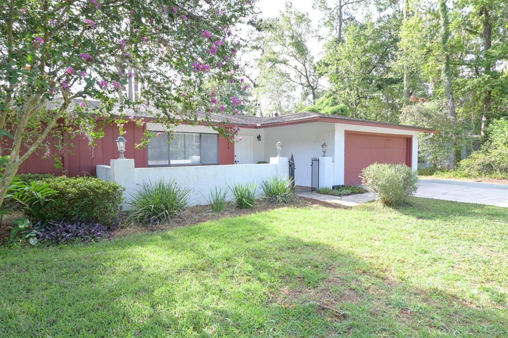 A single-story house with red siding, a white stucco wall, and an attached garage — 3511 NW 40TH TERRACE, GAINESVILLE, FL