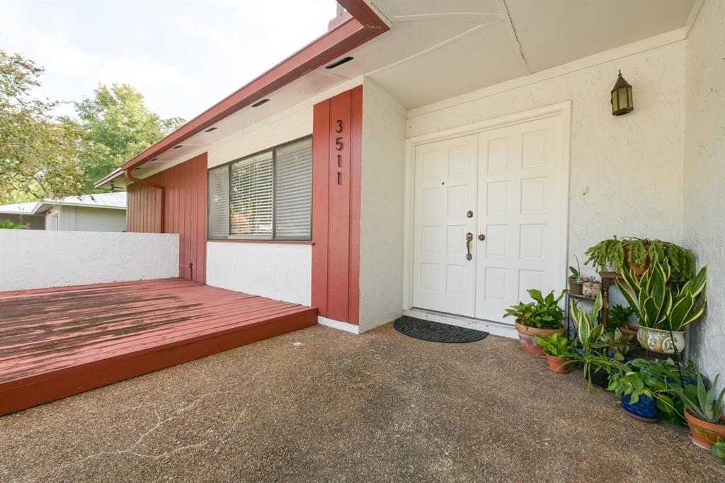 A front entryway features a red wooden deck, white double doors, and potted plants — 3511 NW 40TH TERRACE, GAINESVILLE, FL