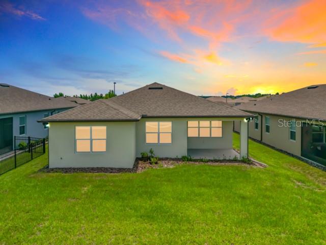The rear exterior of a single-story house features a covered patio and a grassy yard — 8989 SW 57TH PLACE ROAD, OCALA, FL