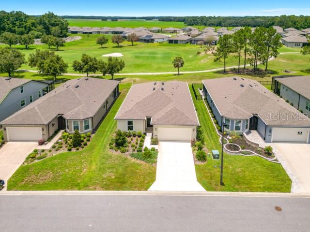 An aerial view shows three suburban houses with driveways facing a street and a golf course — 8989 SW 57TH PLACE ROAD, OCALA, FL