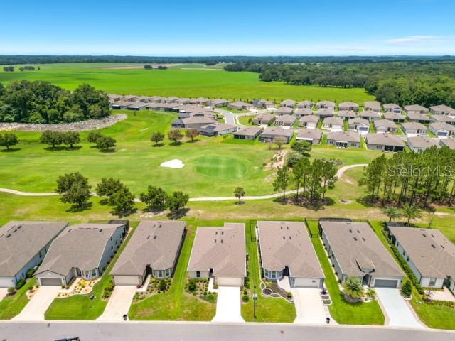 An aerial view shows a suburban neighborhood bordering a golf course and open green fields — 8989 SW 57TH PLACE ROAD, OCALA, FL