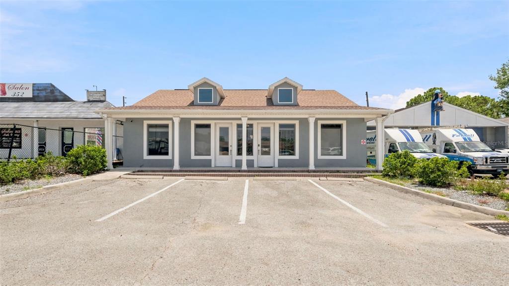 A single-story commercial building with a gray facade, two dormer windows, and a parking lot — 2120 MARINER BOULEVARD, SPRING HILL, FL