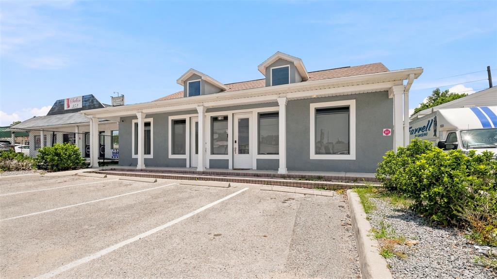 A gray commercial building with a covered porch and parking lot in front — 2120 MARINER BOULEVARD, SPRING HILL, FL