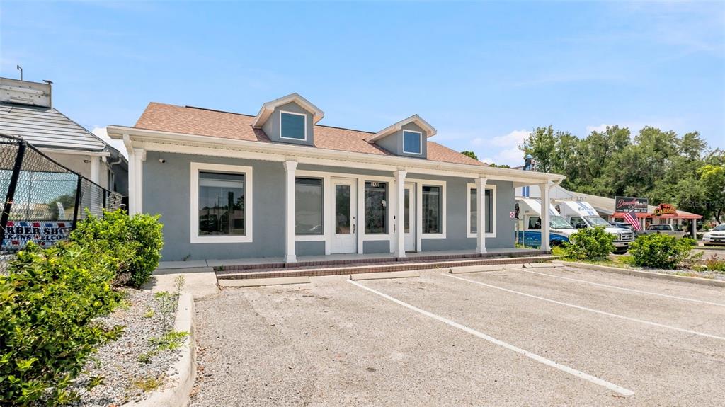 A single-story gray commercial building with a parking lot and two dormer windows — 2120 MARINER BOULEVARD, SPRING HILL, FL