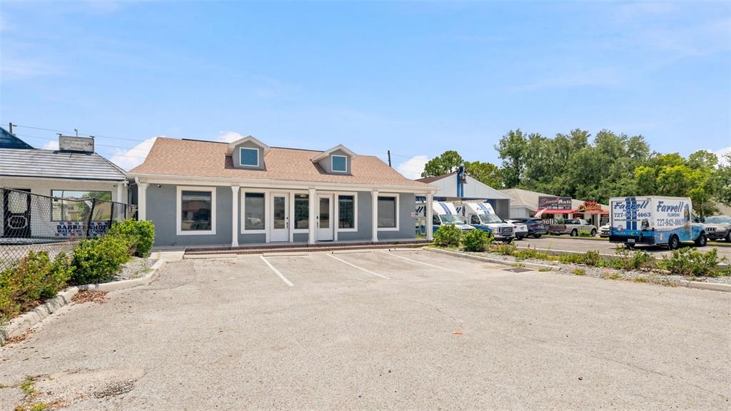 A gray commercial building with a shingled roof sits behind a paved parking lot — 2120 MARINER BOULEVARD, SPRING HILL, FL
