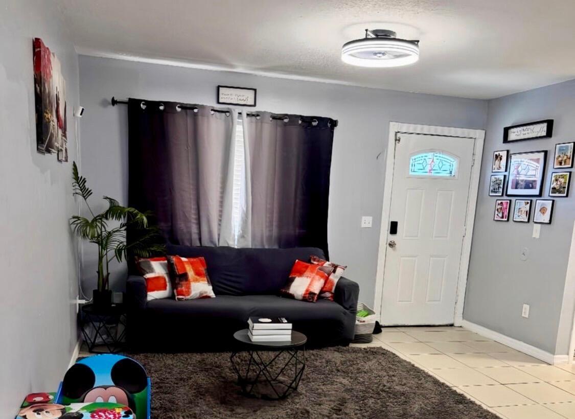A living room features a dark sofa, a round coffee table, and a gray area rug — 190 Abalone Road NW, Palm Bay FL 32907, PALM BAY, FL