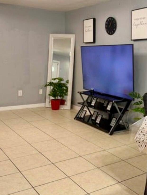 A living room features a television on a glass stand, a floor mirror, and tile flooring — 190 Abalone Road NW, Palm Bay FL 32907, PALM BAY, FL
