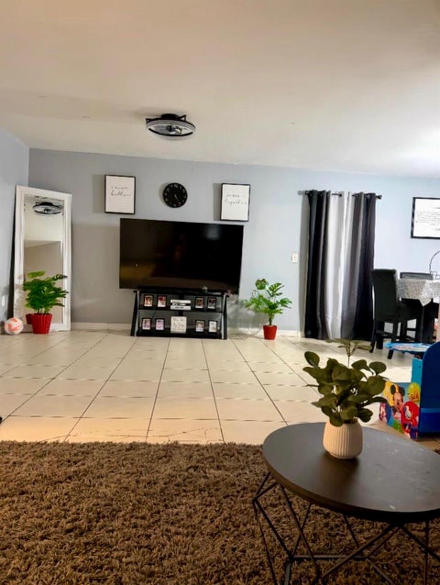 A living room features a television on a stand, tile flooring, and a round coffee table — 190 Abalone Road NW, Palm Bay FL 32907, PALM BAY, FL