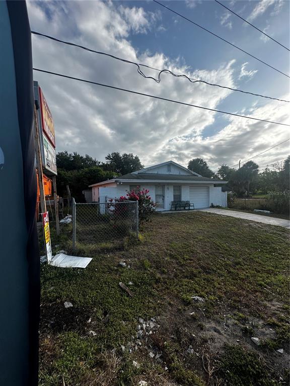 A single-story house with a white exterior and a garage sits behind a chain-link fence — 3350 E STATE ROAD 46, SANFORD, FL
