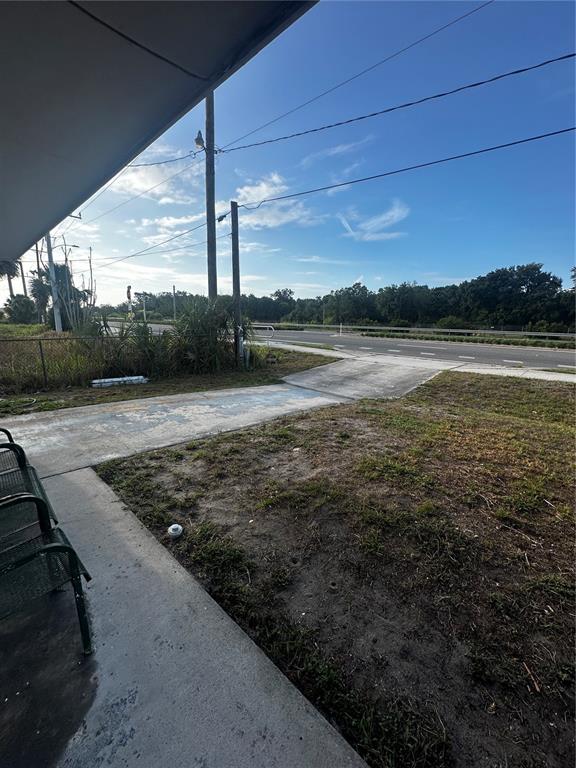 A concrete driveway leads from a covered patio toward a road and wooded area — 3350 E STATE ROAD 46, SANFORD, FL