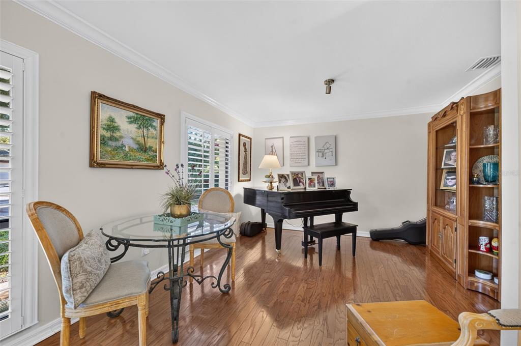 A dining area with a glass table, chairs, and a grand piano on hardwood floors — 823 WOODS COURT, MAITLAND, FL