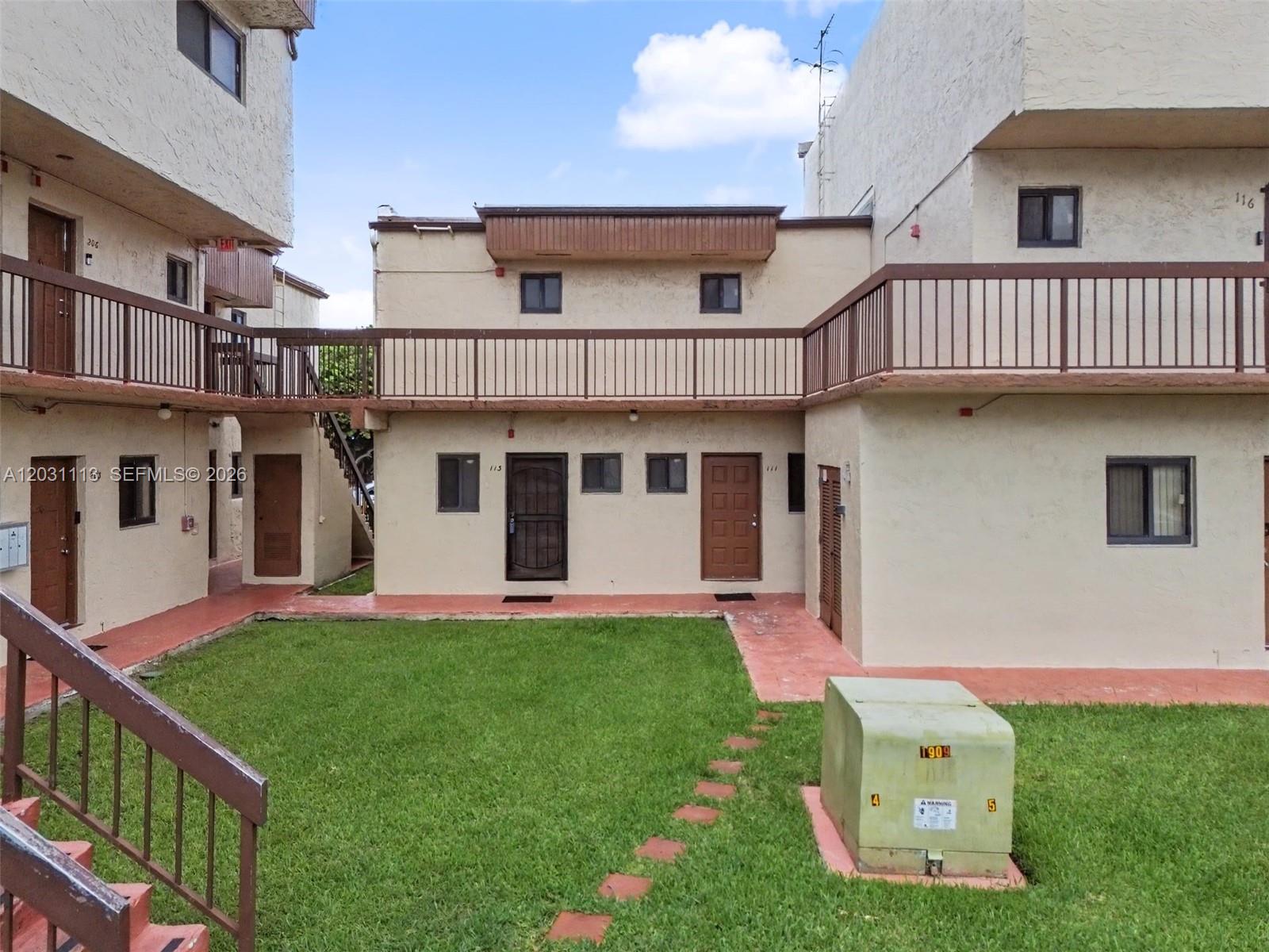 An exterior view of a two-story apartment complex with a central grassy courtyard — 1001 SW 105 Ave # 113, Miami FL 33174, MIAMI, FL