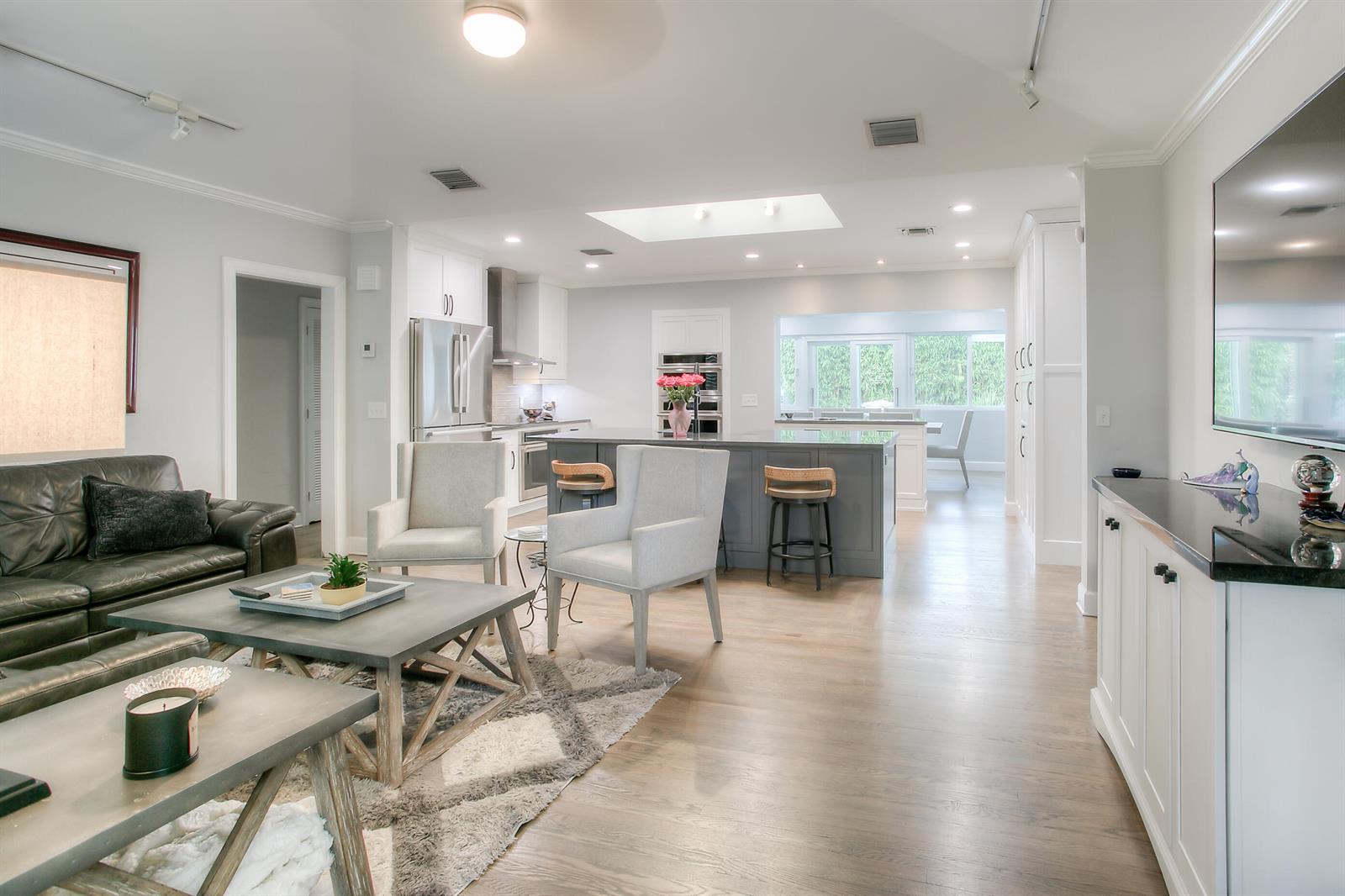 An open-concept living room and kitchen featuring hardwood floors, a gray island, and white cabinetry — 322 NW 16th Street, Delray Beach FL 33444, DELRAY BEACH, FL