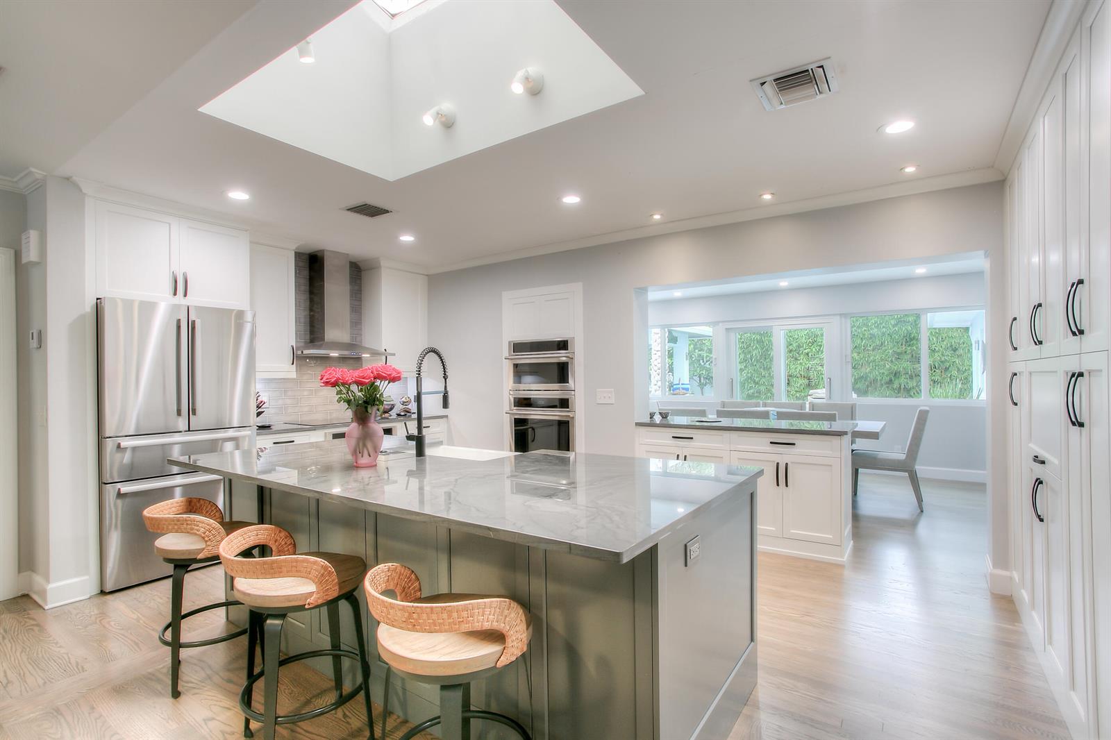 A modern kitchen features a large gray island, white cabinetry, stainless appliances, and a skylight — 322 NW 16th Street, Delray Beach FL 33444, DELRAY BEACH, FL