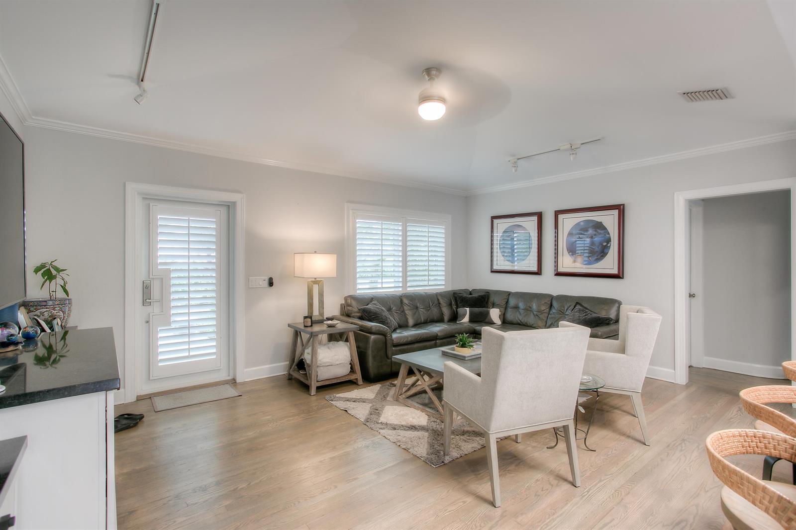 A living room features a dark leather sectional, two light chairs, and hardwood flooring — 322 NW 16th Street, Delray Beach FL 33444, DELRAY BEACH, FL