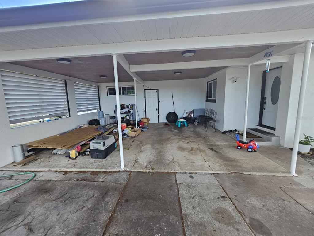 A covered carport with a concrete floor, white support columns, and various stored items — 2800 S FRENCH AVENUE, SANFORD, FL