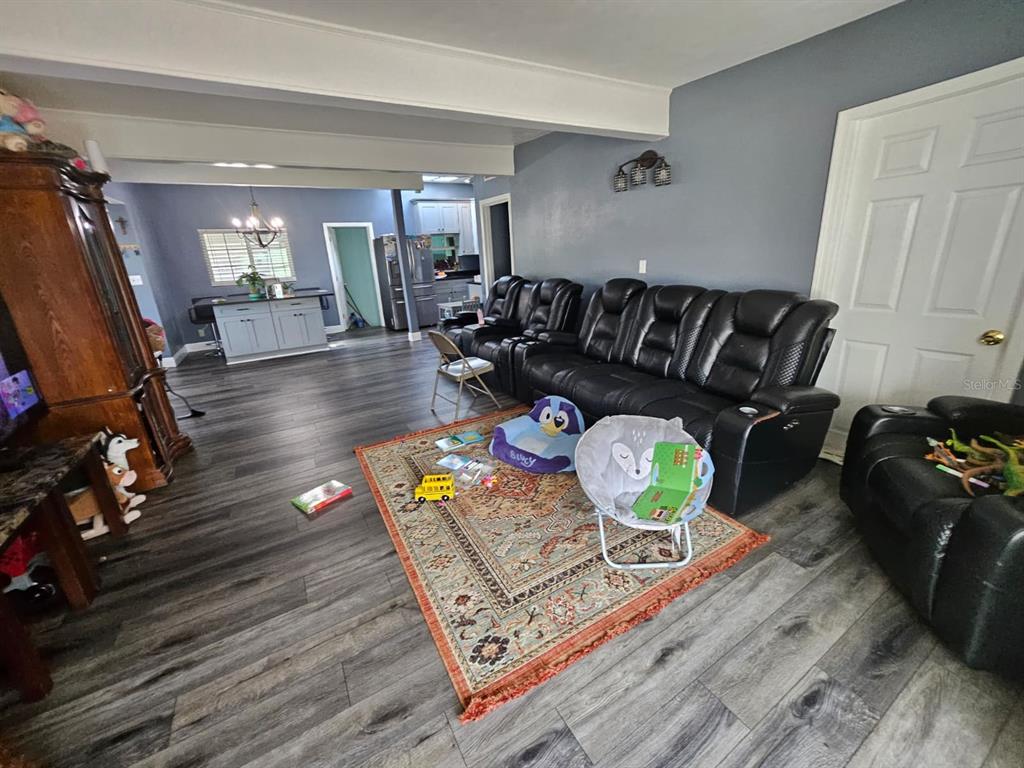 A living room with gray walls, wood-look flooring, a large area rug, and black recliners — 2800 S FRENCH AVENUE, SANFORD, FL