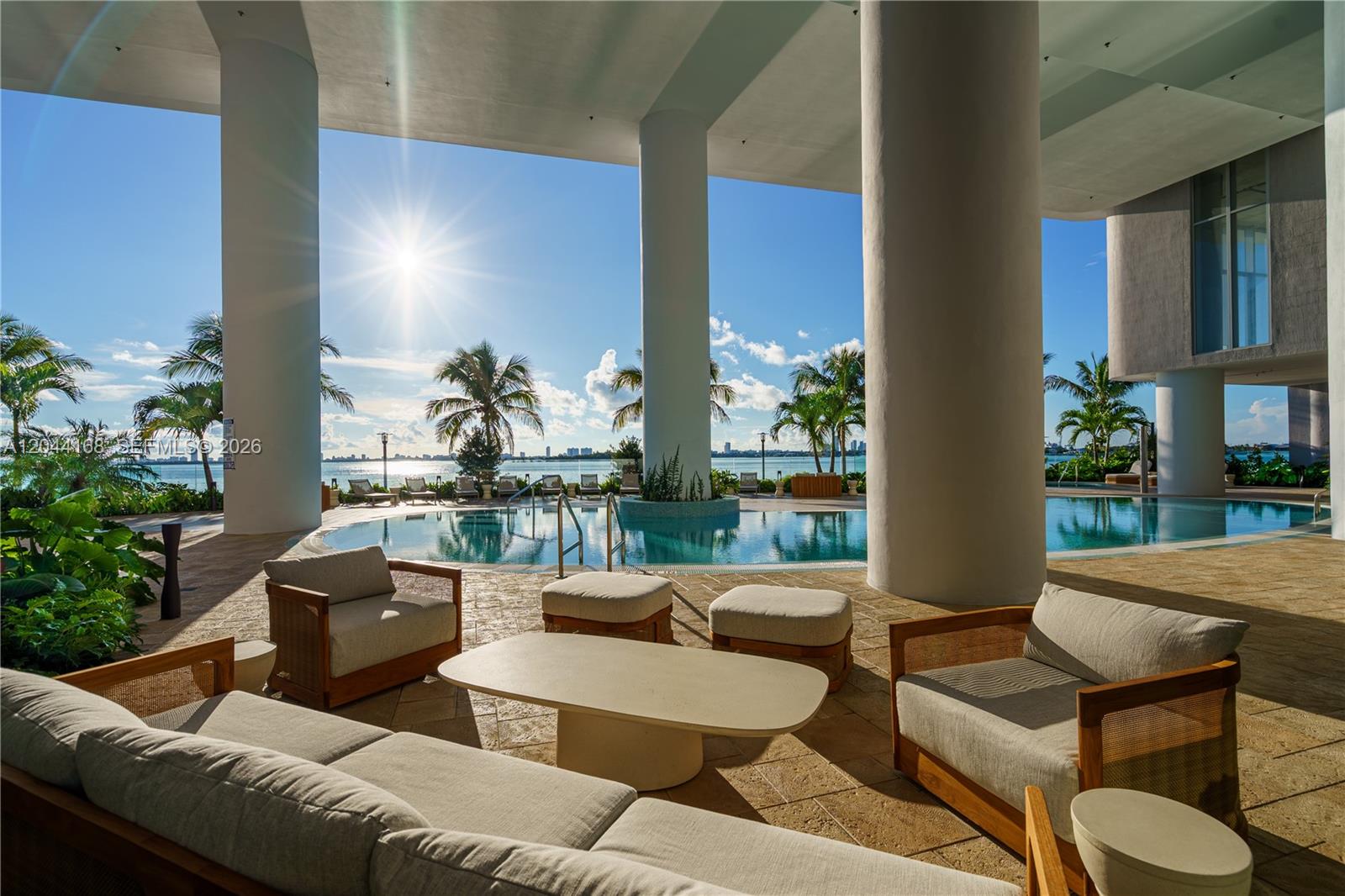 An outdoor lounge area features patio furniture overlooking a swimming pool and the ocean — 700 NE 23rd St # 2304, Miami FL 33137, MIAMI, FL