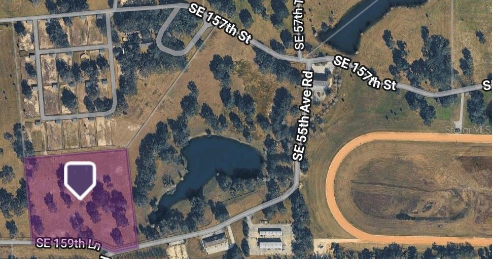 This aerial map shows a vacant, rectangular lot highlighted in purple near a small pond — LOT 25 SE 159TH LANE, SUMMERFIELD, FL