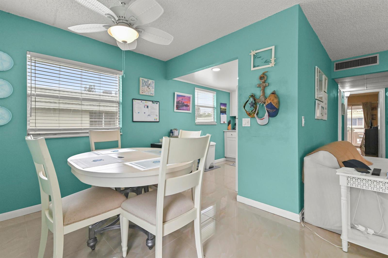 A dining area with a round table, white chairs, and teal walls — 520 Monaco K, Delray Beach FL 33446, DELRAY BEACH, FL
