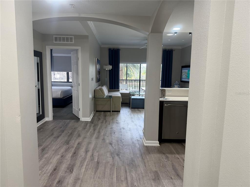 A view from a hallway into a living area with wood-look flooring and a kitchen — 14501 GROVE RESORT AVENUE UNIT 1203, WINTER GARDEN, FL