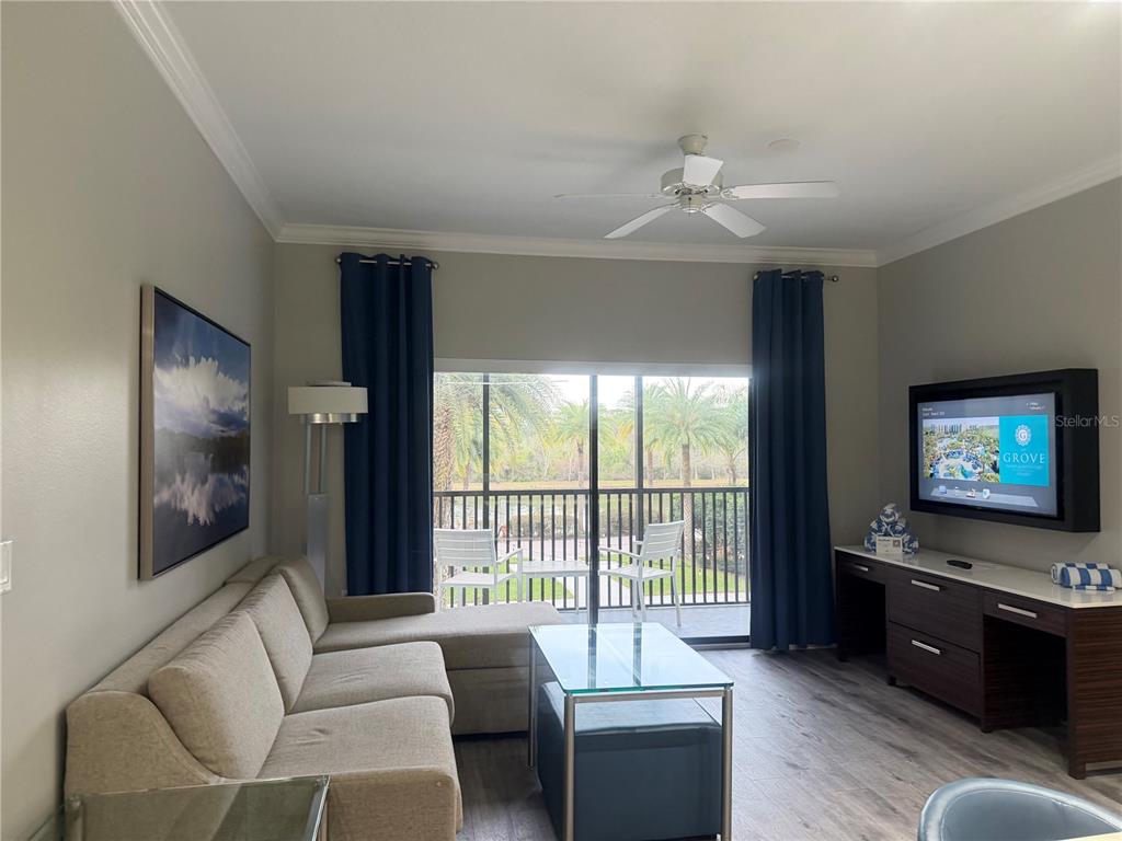 A living room features a sectional sofa, glass coffee table, television, and sliding glass doors — 14501 GROVE RESORT AVENUE UNIT 1203, WINTER GARDEN, FL