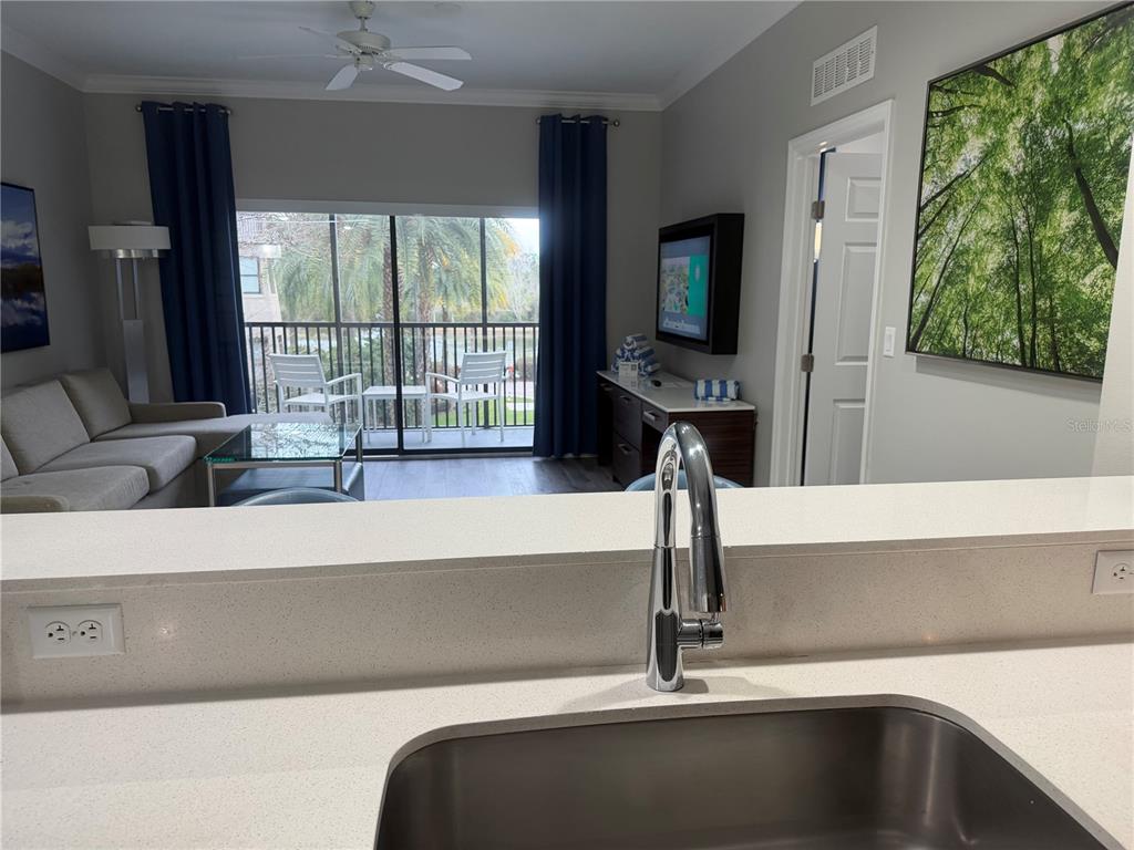 A kitchen sink overlooks a living room with a balcony, sofa, and television — 14501 GROVE RESORT AVENUE UNIT 1203, WINTER GARDEN, FL