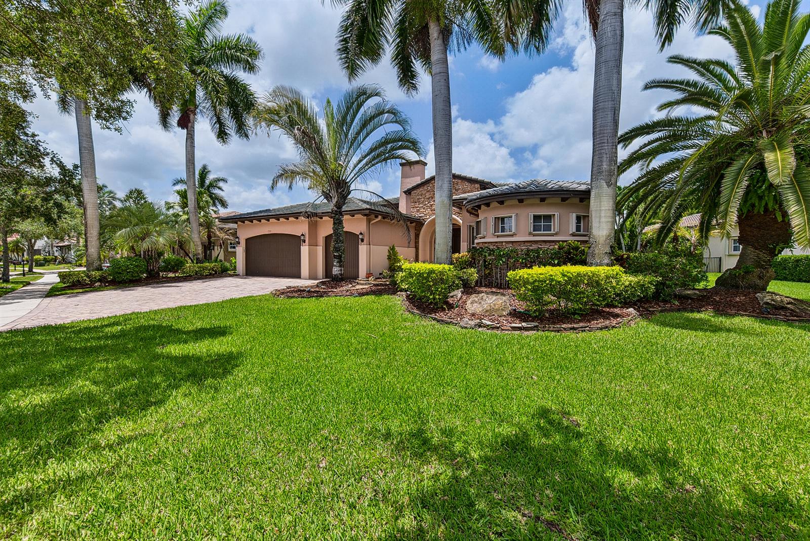 A single-story house with a paved driveway, palm trees, and a circular stone-accented room — 7233 NW 123rd Avenue, Parkland FL 33076, PARKLAND, FL