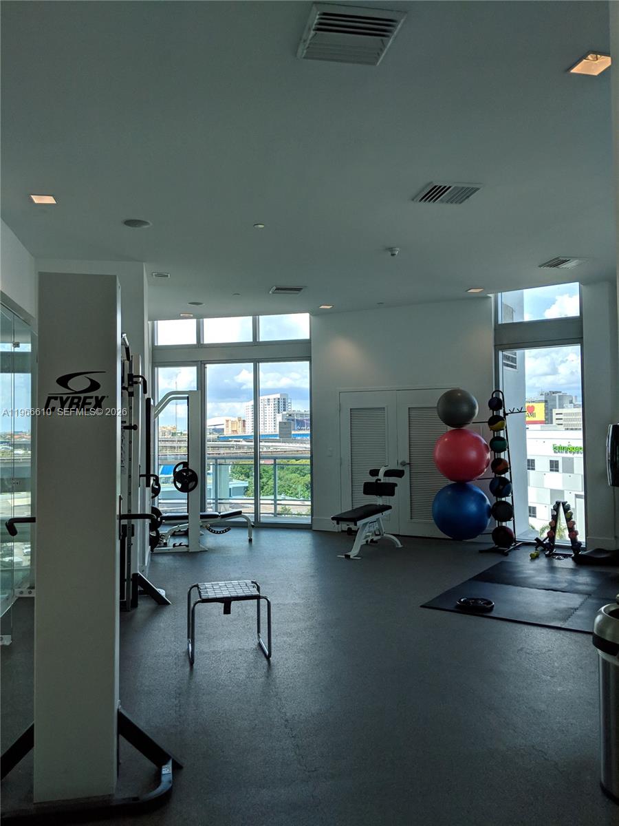 A gym with exercise equipment, rubber flooring, and floor-to-ceiling windows overlooking a city skyline — 350 S Miami Ave # 1901, Miami FL 33130, MIAMI, FL