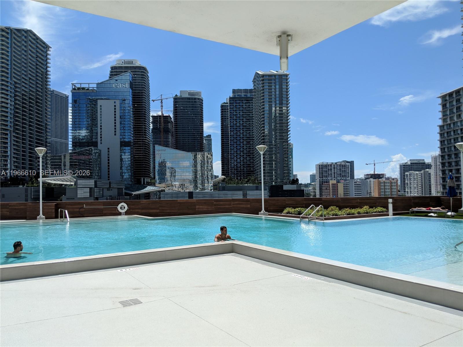 An outdoor swimming pool overlooks a city skyline with tall skyscrapers under a blue sky — 350 S Miami Ave # 1901, Miami FL 33130, MIAMI, FL