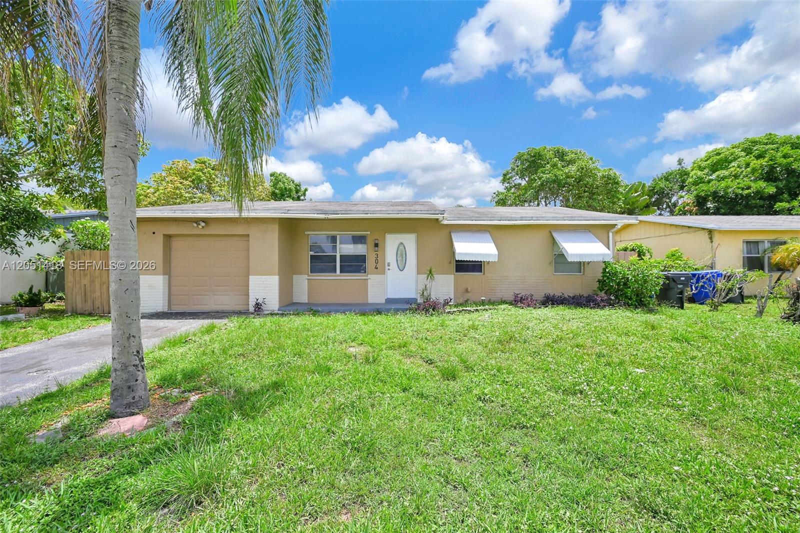 A single-story house with a tan exterior, a garage, and a front lawn — 304 SW 77th Ave, North Lauderdale FL 33068, NORTH LAUDERDALE, FL