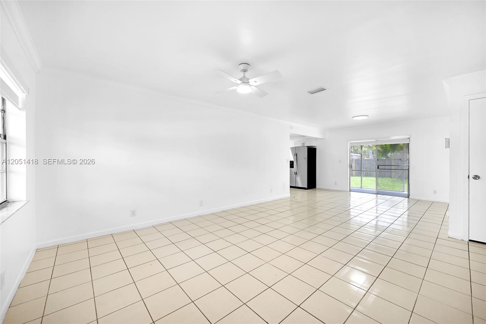 An empty room features white walls, light-colored tile flooring, a ceiling fan, and sliding doors — 304 SW 77th Ave, North Lauderdale FL 33068, NORTH LAUDERDALE, FL
