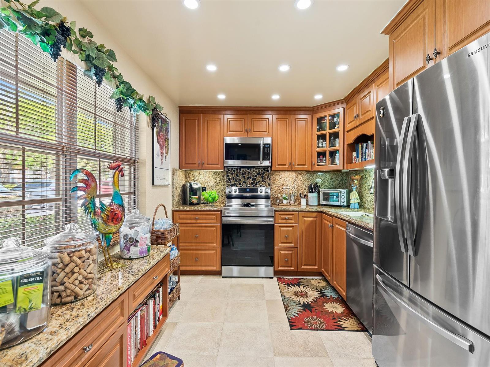 A kitchen with wood cabinets, granite countertops, stainless steel appliances, and a rooster figurine — 4221 W Palm Aire Drive # 102, Pompano Beach FL 33069, POMPANO BEACH, FL