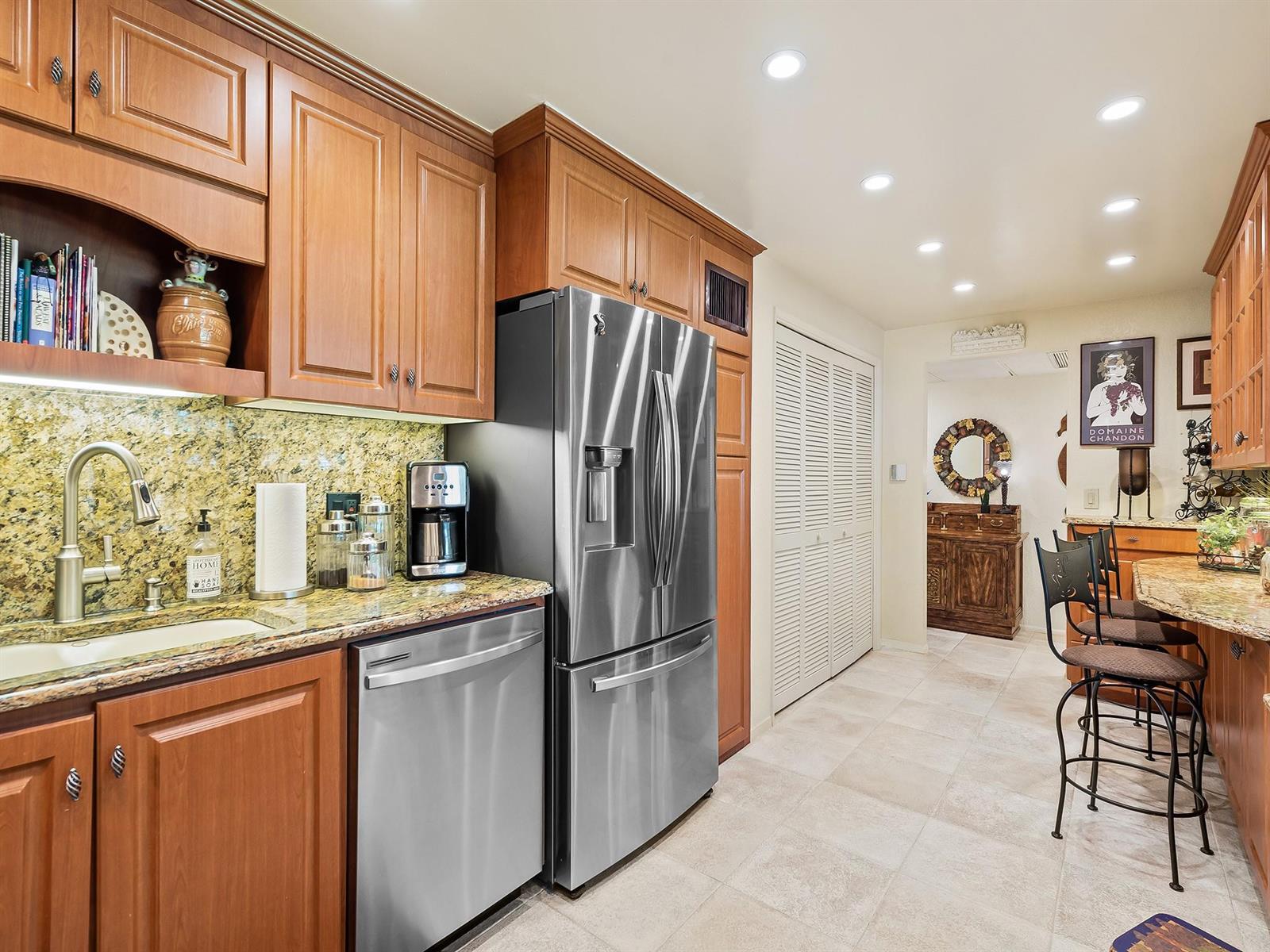 A kitchen with wood cabinets, stainless steel appliances, granite countertops, and a breakfast bar — 4221 W Palm Aire Drive # 102, Pompano Beach FL 33069, POMPANO BEACH, FL