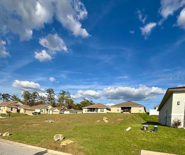 A grassy lot sits in front of several suburban houses under a blue sky — 4537 NW 1ST TERRACE, OCALA, FL