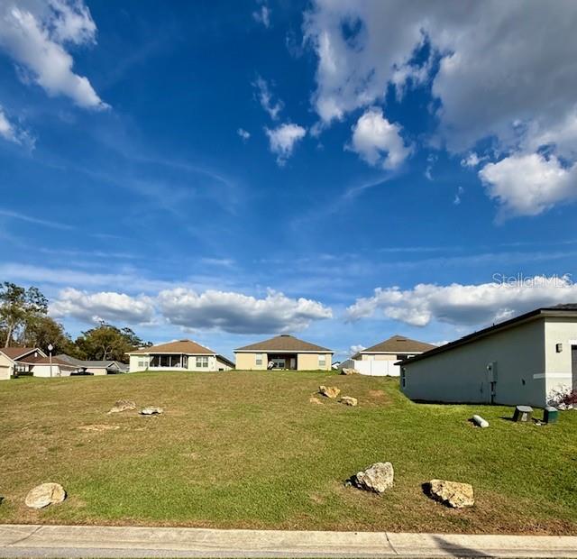 A grassy, vacant residential lot sits in front of several suburban houses under a blue sky — 4537 NW 1ST TERRACE, OCALA, FL
