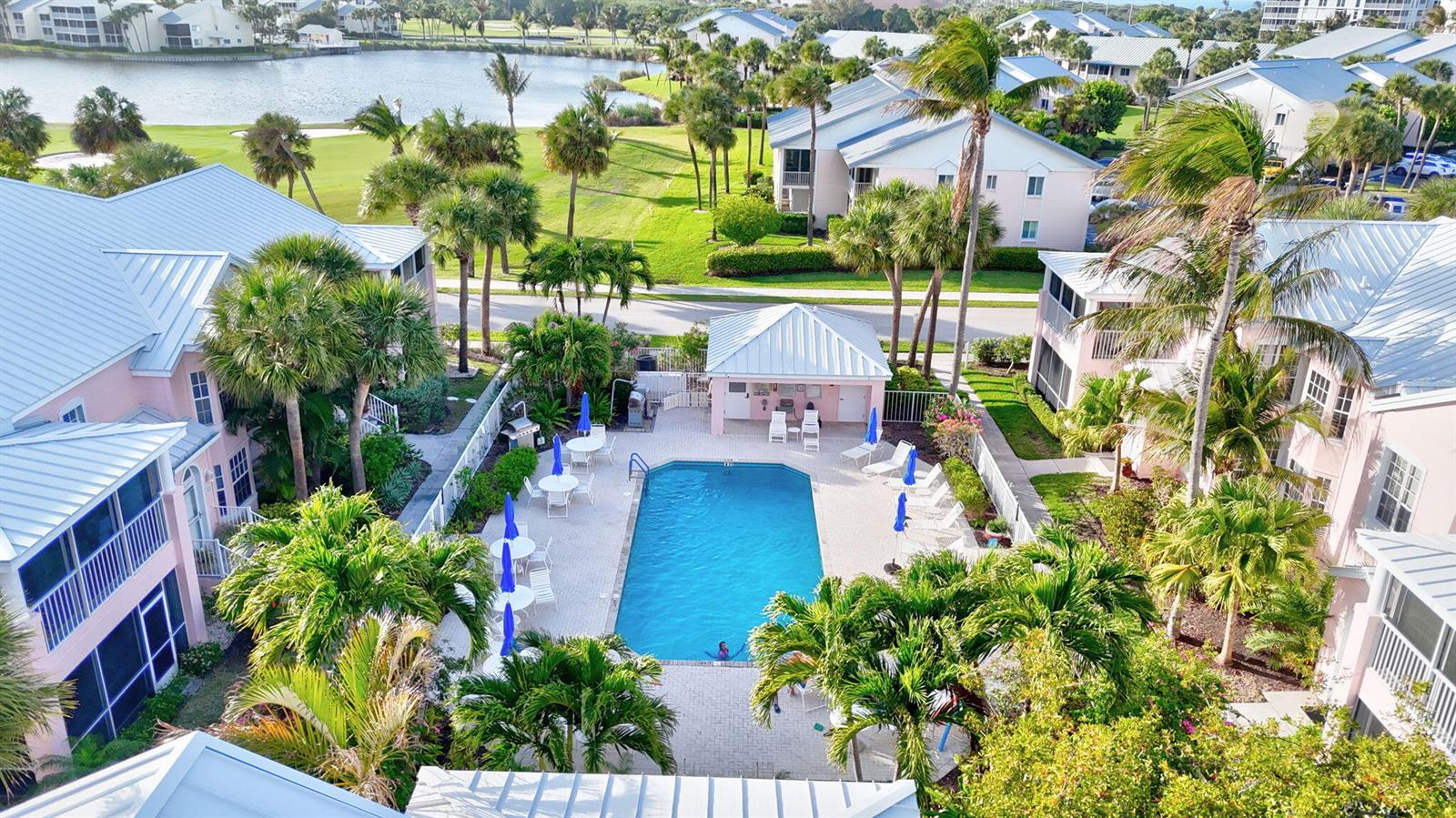 An aerial view of a swimming pool surrounded by palm trees and multi-story residential buildings — 421 NE Plantation # 617, Stuart FL 34996, STUART, FL