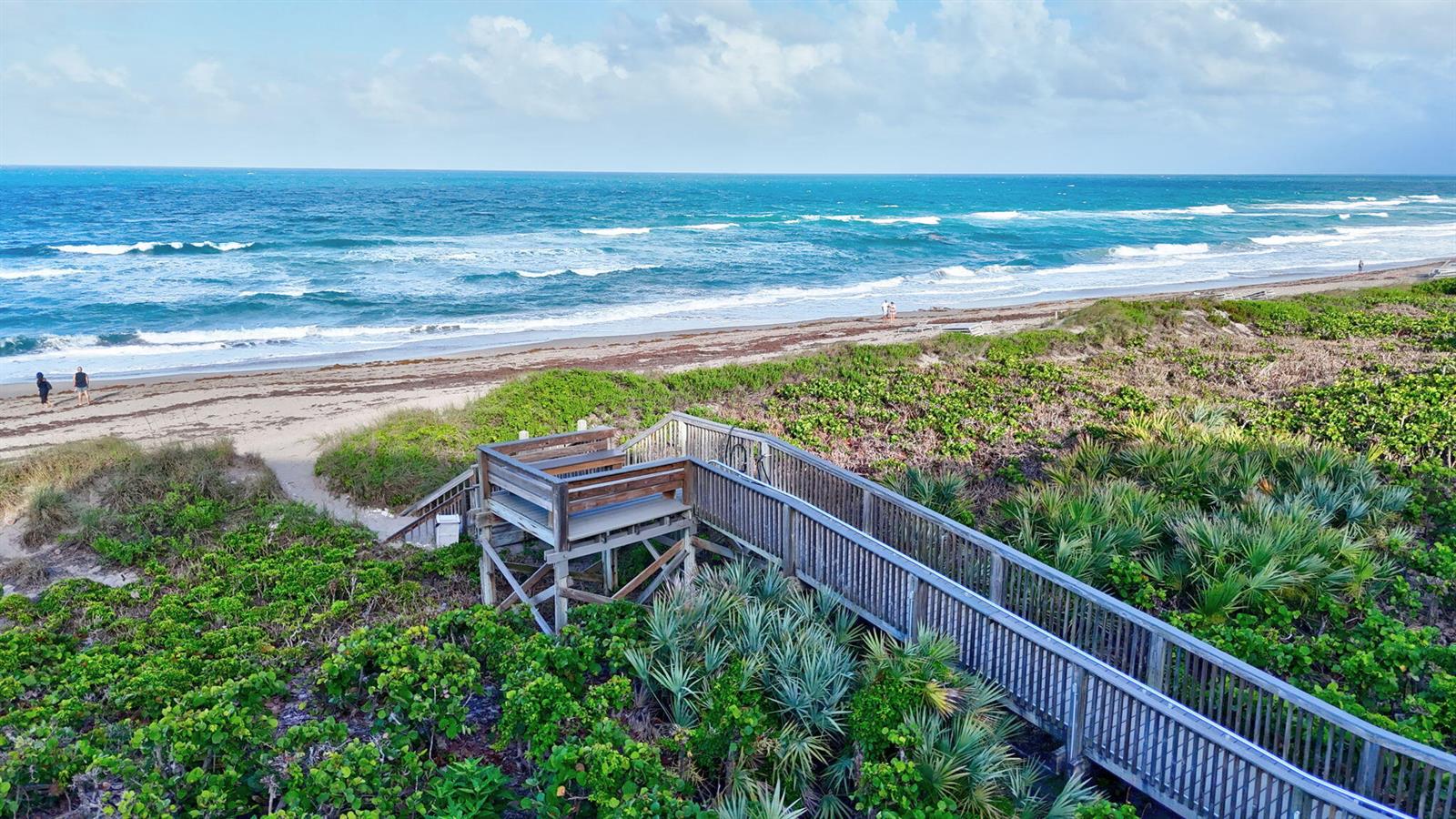 A wooden boardwalk leads through coastal vegetation to a sandy beach and the ocean — 421 NE Plantation # 617, Stuart FL 34996, STUART, FL