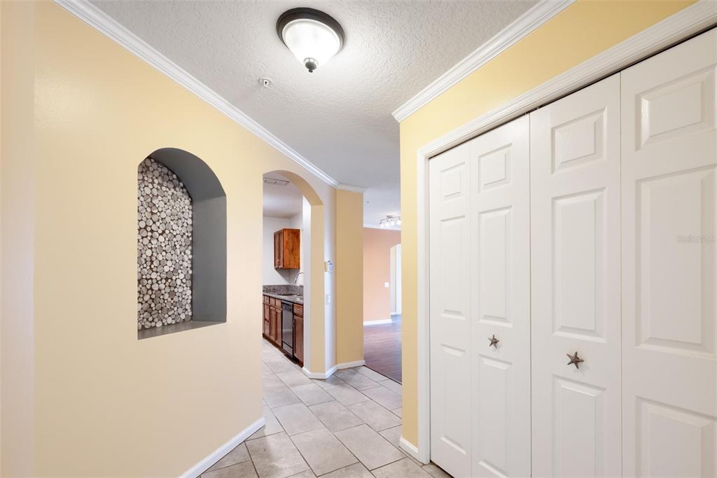 A hallway with tiled floors, a decorative arched wall niche, and white bi-fold closet doors — 3930 SOUTHPOINTE DRIVE UNIT 213, ORLANDO, FL