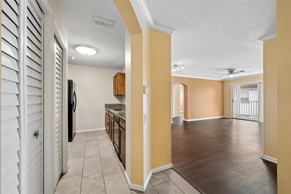 A view from a tiled hallway into a kitchen and a living room with wood floors — 3930 SOUTHPOINTE DRIVE UNIT 213, ORLANDO, FL