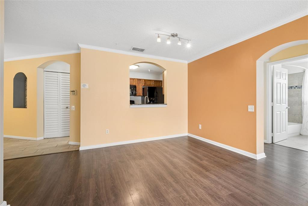 An interior room with wood-look flooring, two-tone walls, a kitchen pass-through, and a bathroom doorway — 3930 SOUTHPOINTE DRIVE UNIT 213, ORLANDO, FL