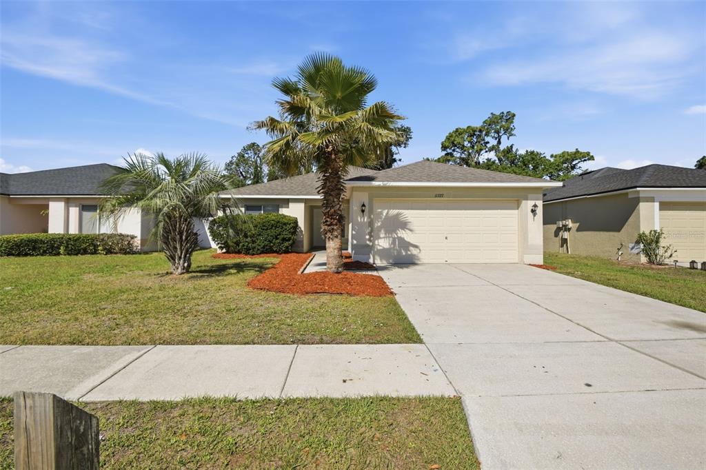 A single-story house with a beige exterior, a two-car garage, and a palm tree — 11727 BRENFORD CREST DRIVE, RIVERVIEW, FL